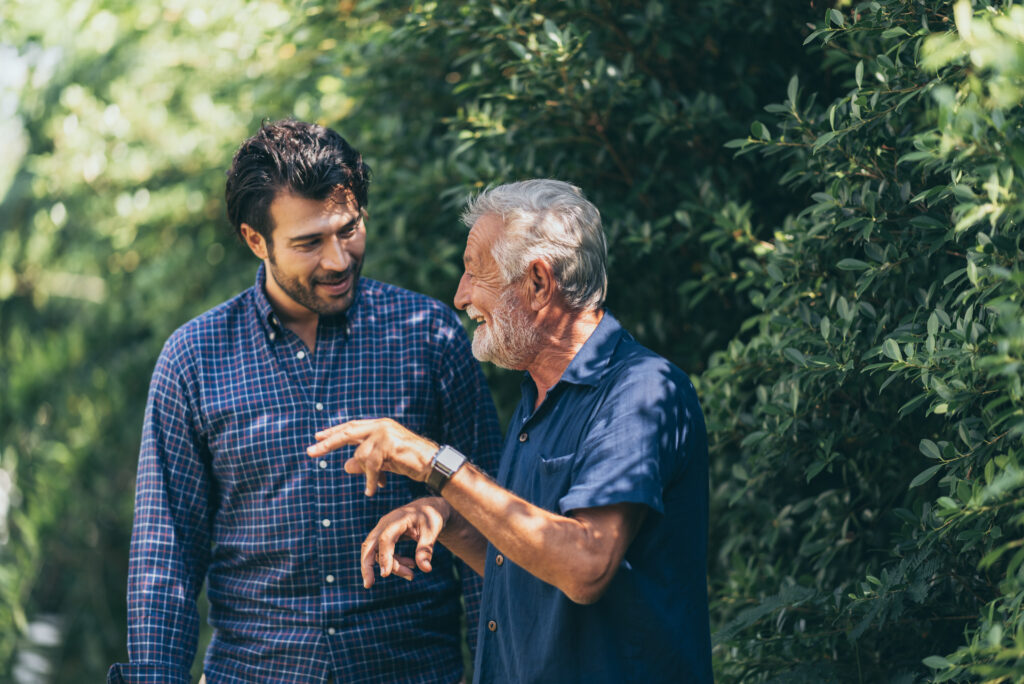 old father and adult son are relaxing in the backyard